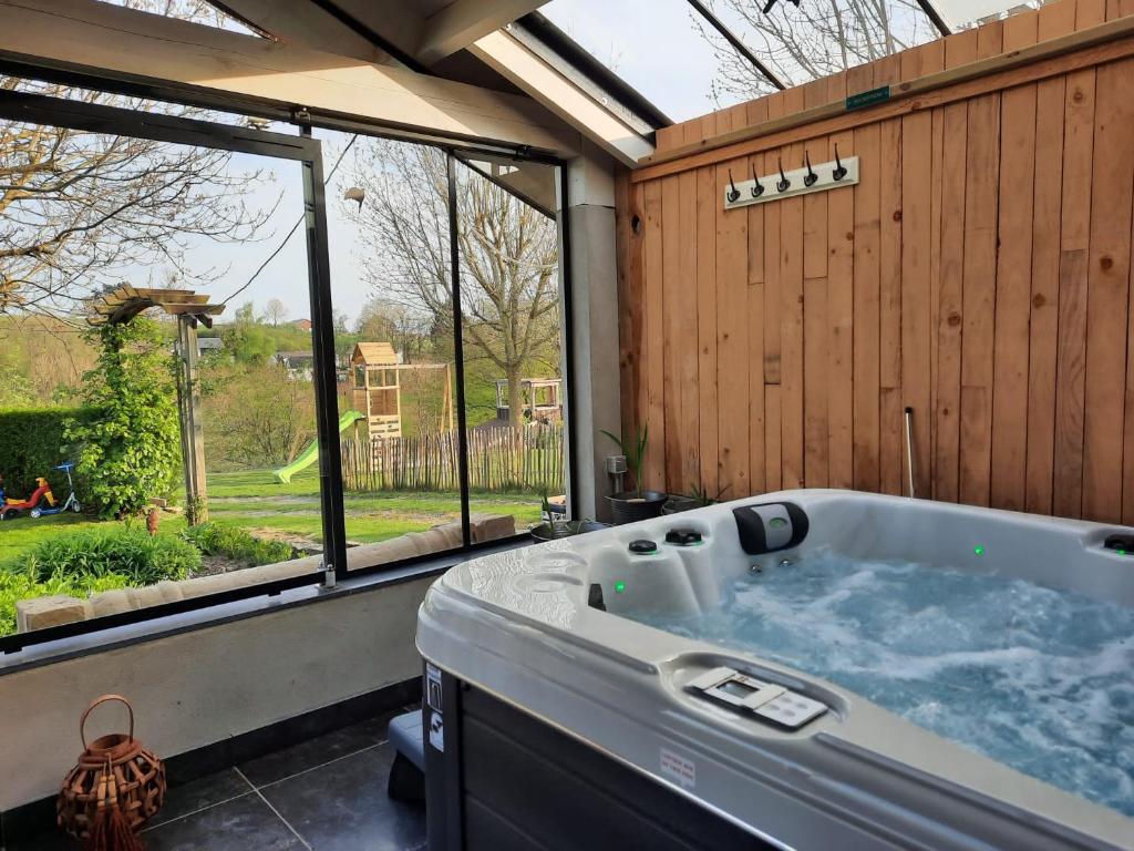 a large tub in a room with a large window at La Vieille Forge in Houffalize