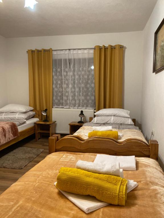 1 dormitorio con 2 camas y una ventana con cortinas amarillas en Kuća za odmor KOD DOZA, en Gospić
