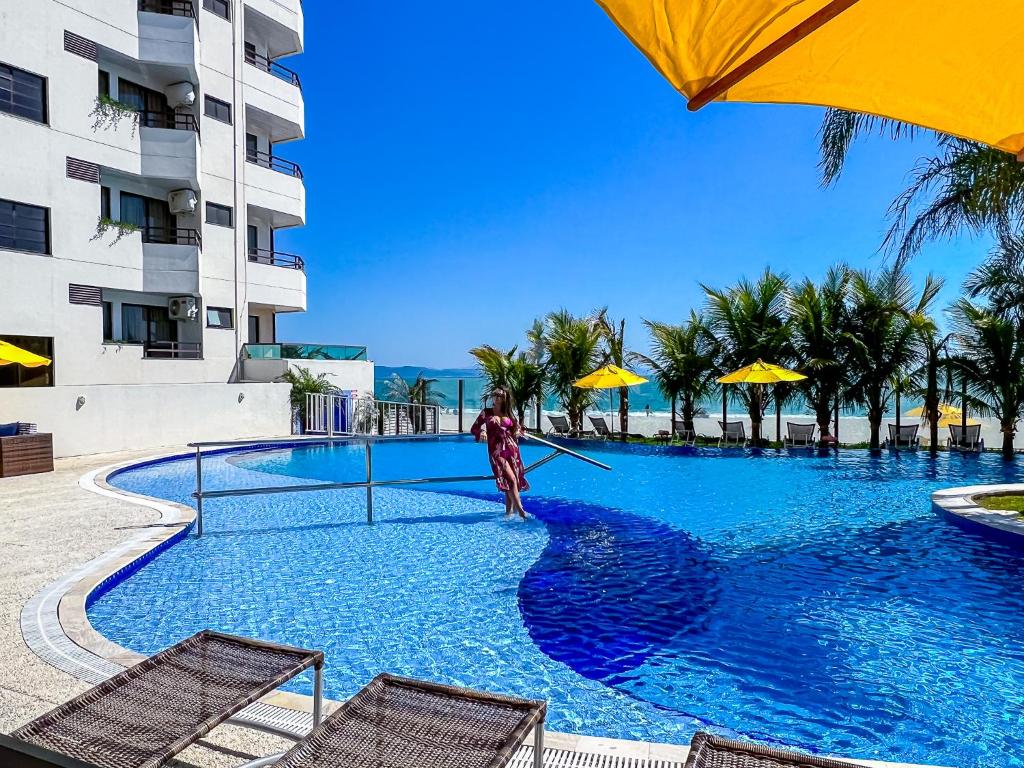 un uomo è in piedi accanto a una piscina di Hotel Palace 1 a Florianópolis