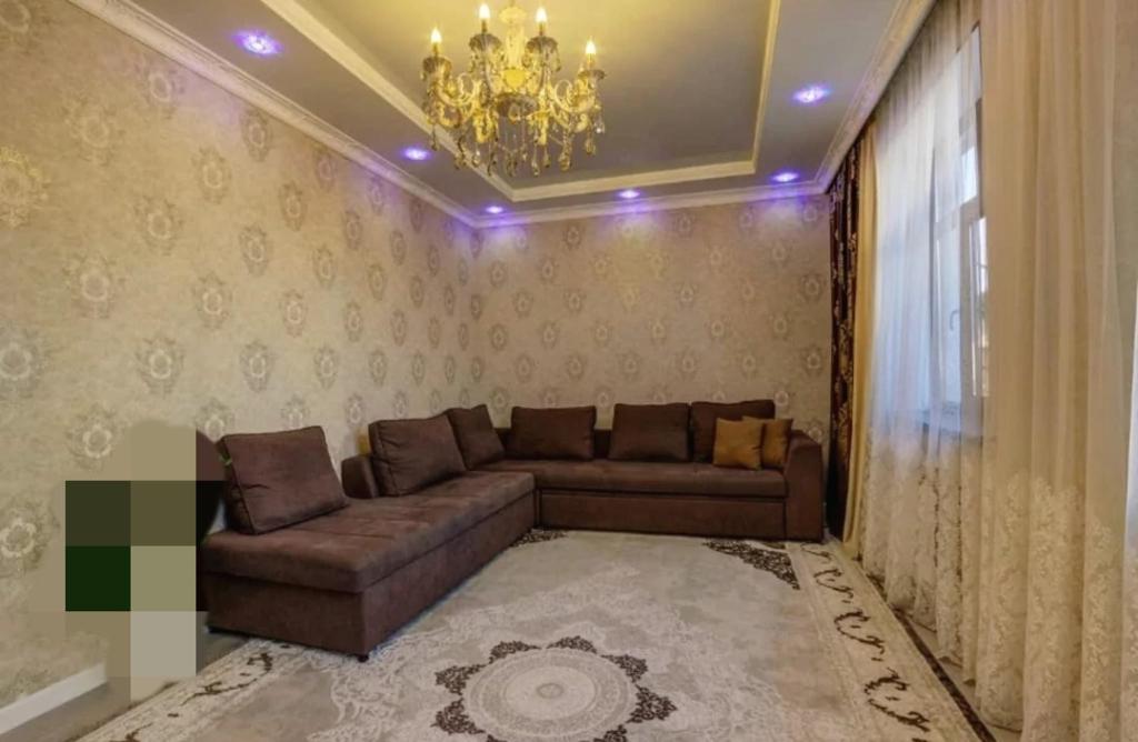 sala de estar con sofá y lámpara de araña en Quite Villa, en Bishkek