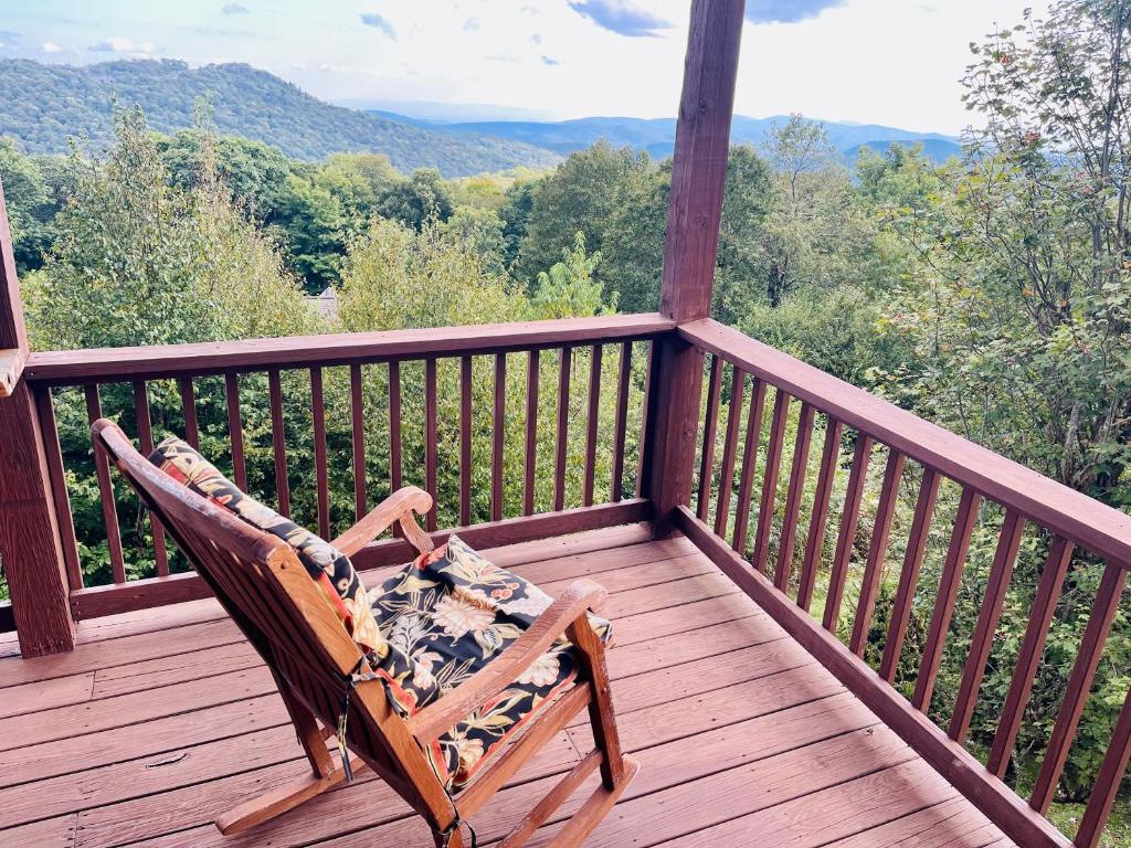a rocking chair sitting on a wooden deck with a view at Bucket List Views Ski In Out Sugar Mountain Cabin in Sugar Mountain