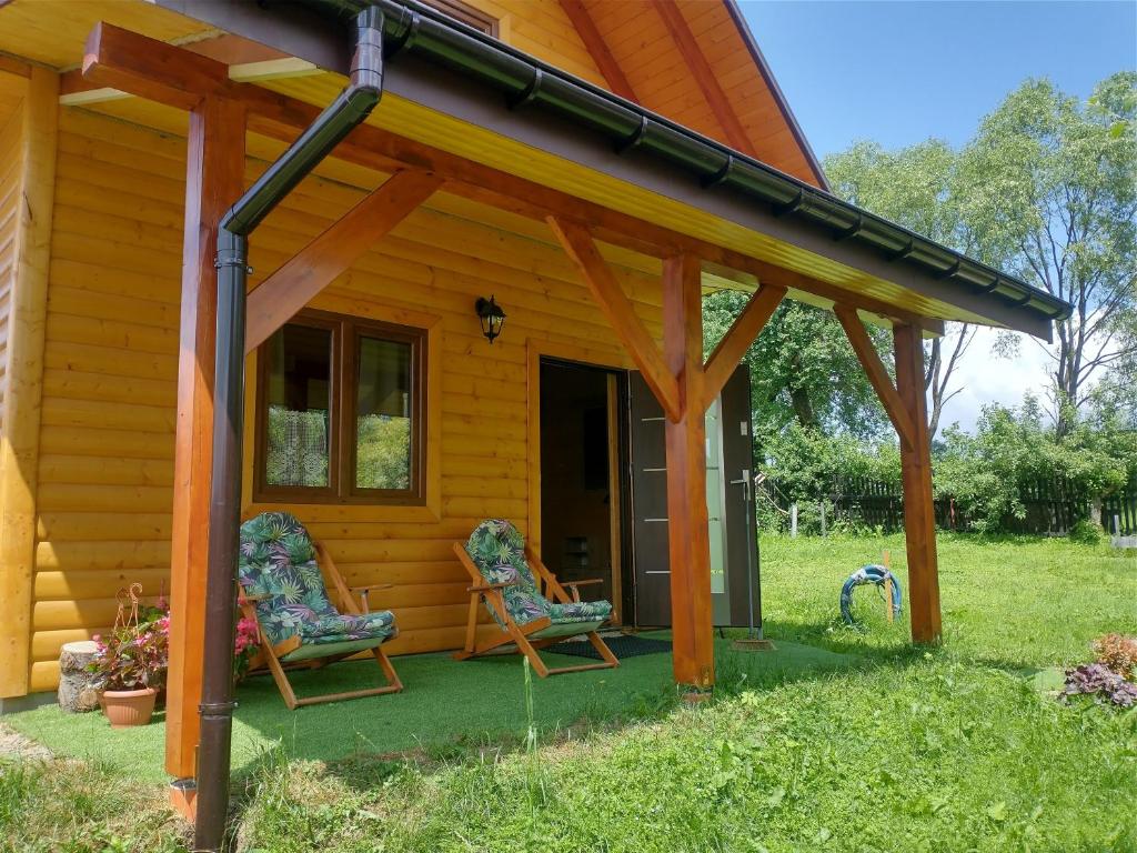 a wooden cabin with two chairs on the porch at Noclegi Żurawin in Lutowiska