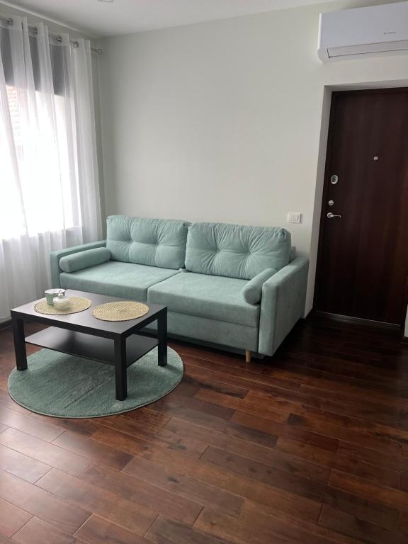 ein Wohnzimmer mit einem Sofa und einem Couchtisch in der Unterkunft ŽALI apartamentai Šilutė in Šilutė