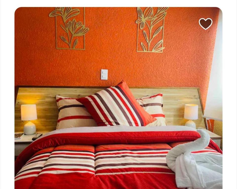 a bedroom with a bed with an orange wall at Habitación Deluxe in Orizaba