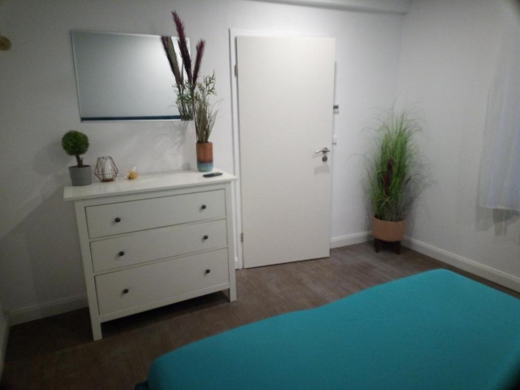 ein Schlafzimmer mit einem Bett und einer Kommode mit Pflanzen in der Unterkunft Helle und gemütliche 2 Zimmer Ferienwohnung in Ludwigsburg
