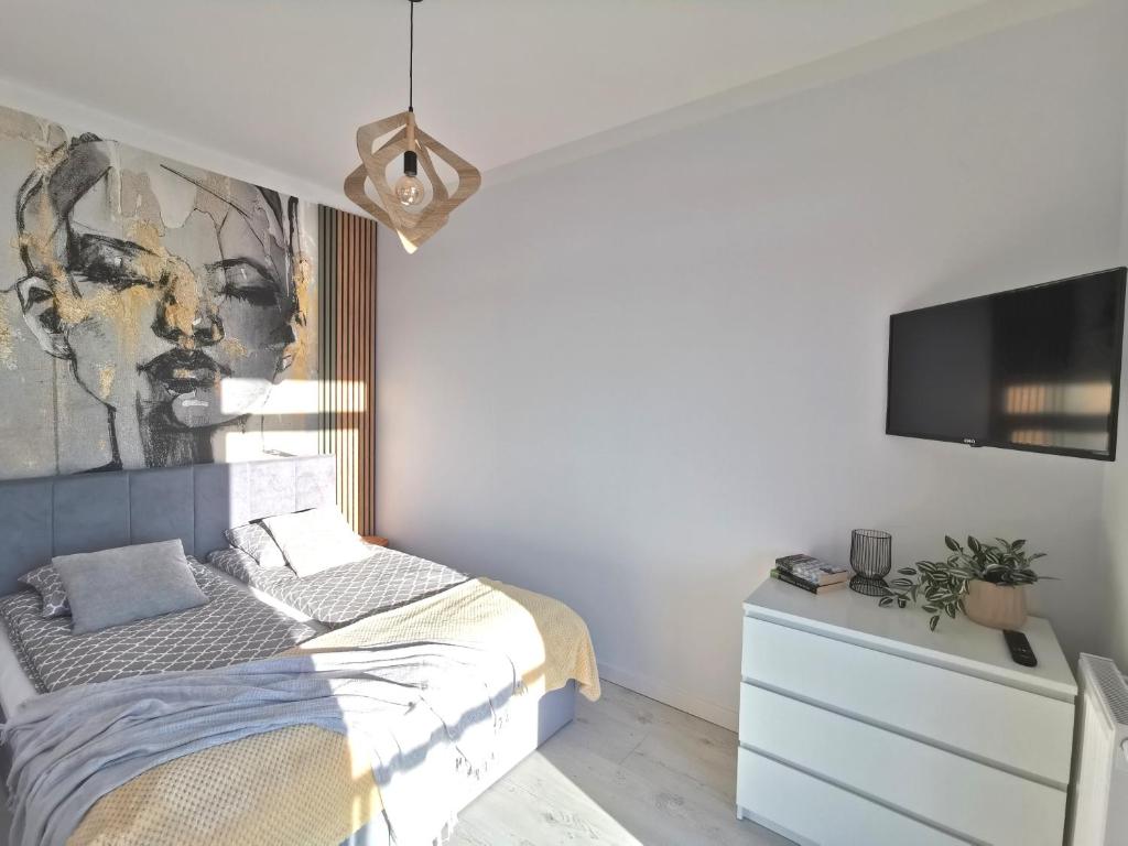 a bedroom with a bed and a tv on a wall at Apartamenty Wybrzeże Laguna - Ku Morzu in Sianozety