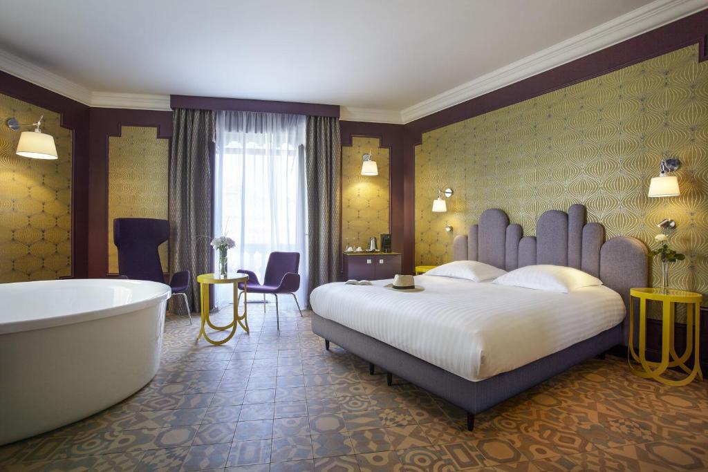a hotel room with a bed and a bath tub at Grand Hôtel du Midi Montpellier - Opéra Comédie in Montpellier
