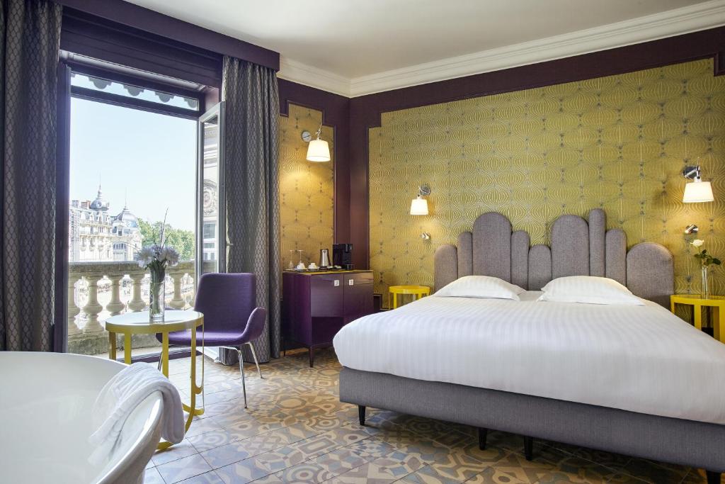 a hotel room with two beds and a chair at Grand Hôtel du Midi Montpellier - Opéra Comédie in Montpellier