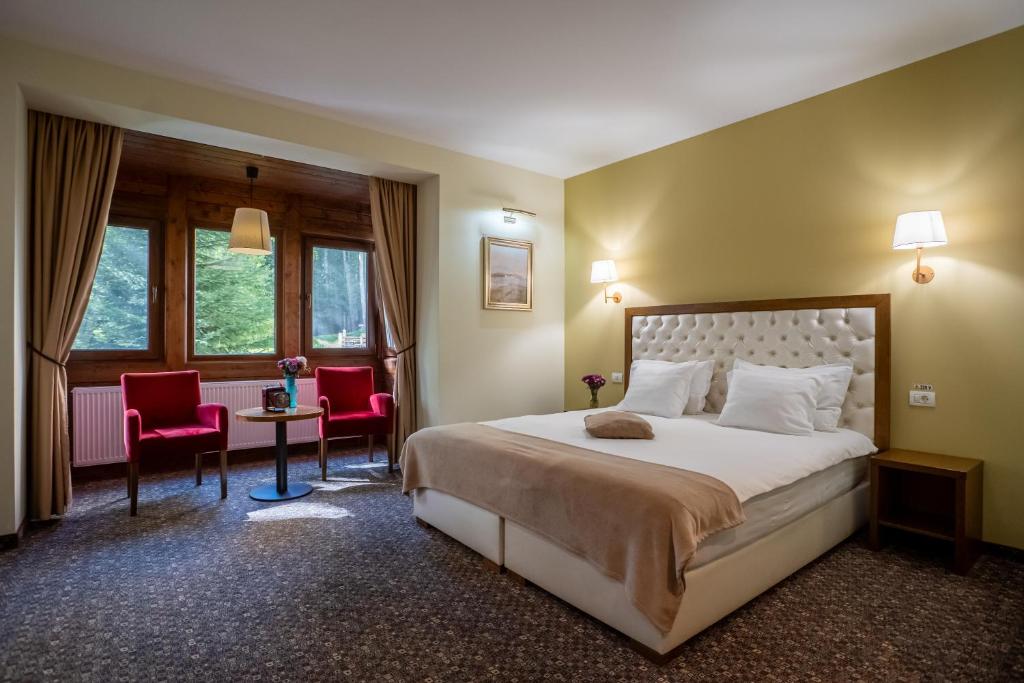 une chambre d'hôtel avec un lit, une table et des chaises dans l'établissement Opus Villa, à Sinaia