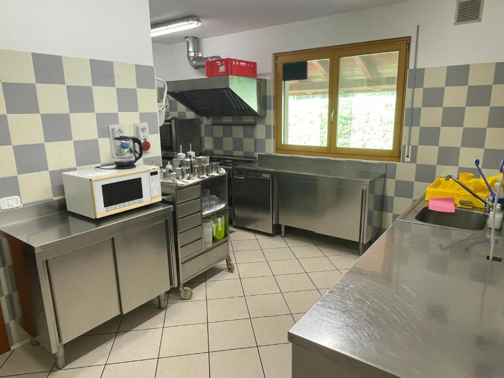 a kitchen with stainless steel appliances and a microwave at Lunga Via Delle Dolomiti in Calalzo