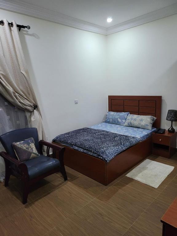 1 dormitorio con 1 cama y 1 silla en BDA APARTMENT - Netflix, Free Wi-Fi, PlayStation 4, Kitchen, Supermarket, Pharmacy, Laundry & 24hours Electricity, en Abuja
