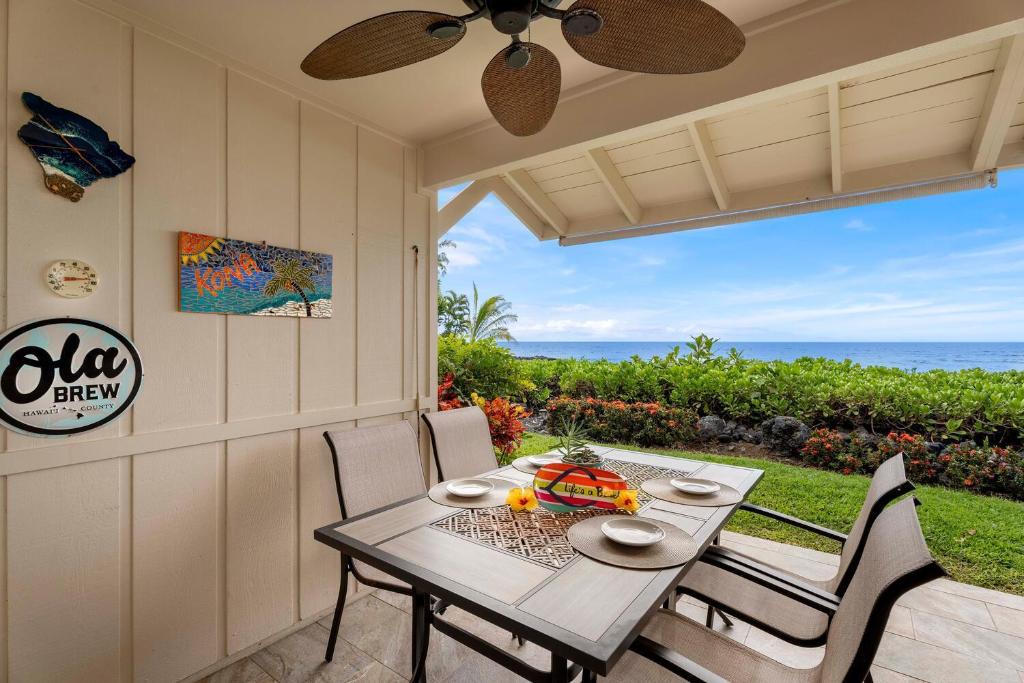 a table and chairs on a patio with a view of the ocean at Keauhou Kona Surf & Racket Club Townhouse #3 in Kailua-Kona