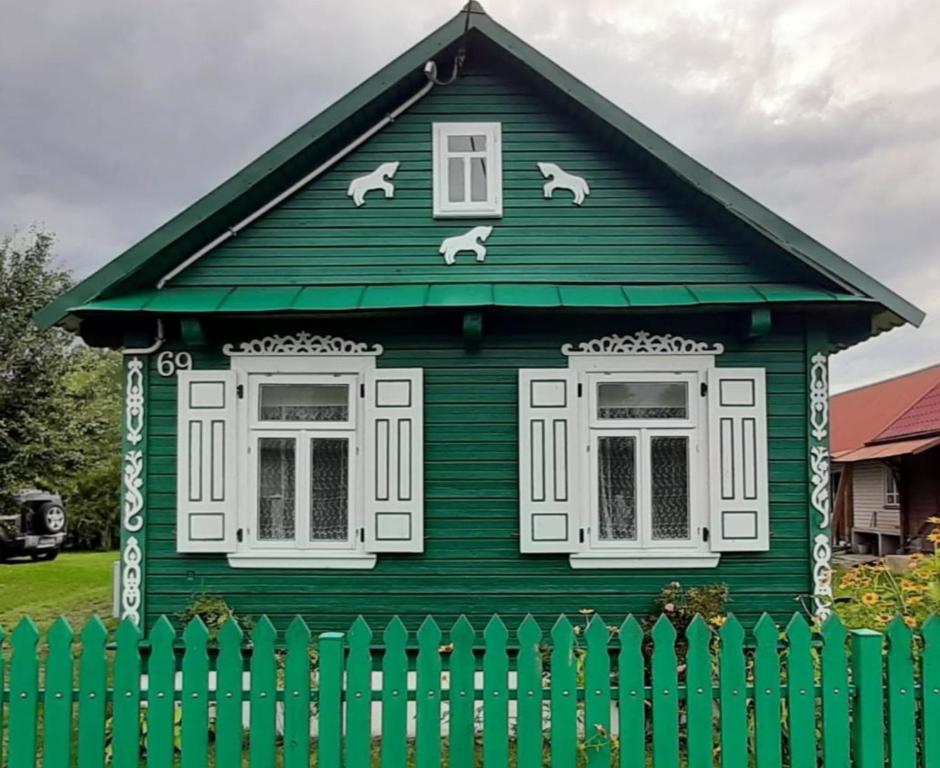ein grünes Haus mit zwei Fenstern und zwei Hunden darauf in der Unterkunft Zielony Domek Plutycze in Plutycze