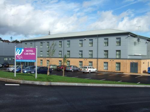 duży budynek z samochodami zaparkowanymi na parkingu w obiekcie The Welcome Inn Rotherham/Sheffield w mieście Rotherham