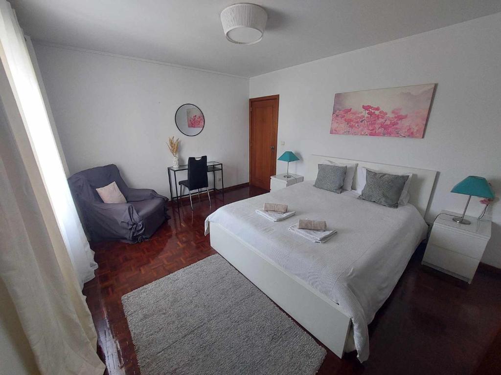 a bedroom with a large white bed and a chair at Vale Formoso Apartment in Porto