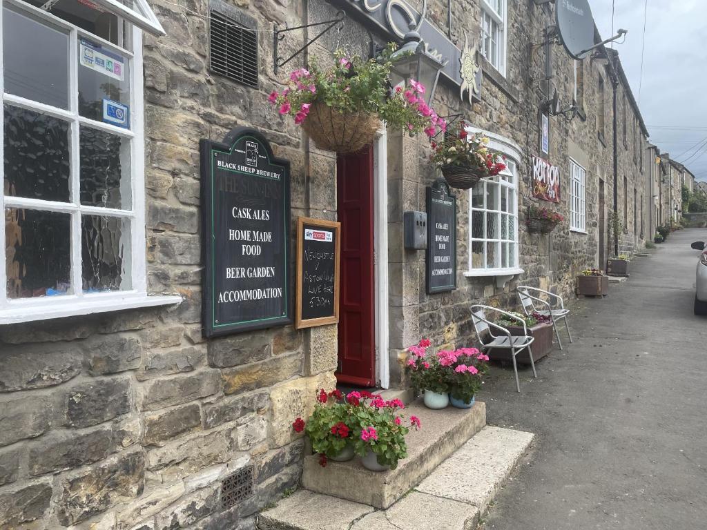 a stone building with potted plants and a sign on it at The Sun Inn in Hexham