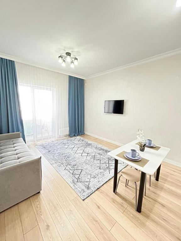 ein Wohnzimmer mit Sofa und Tisch in der Unterkunft Евродвушка вблизи MegaSilkWay & EXPO in Prigorodnyy