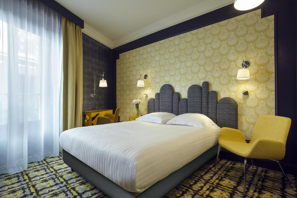 a bedroom with a large bed and a chair at Grand Hôtel du Midi Montpellier - Opéra Comédie in Montpellier