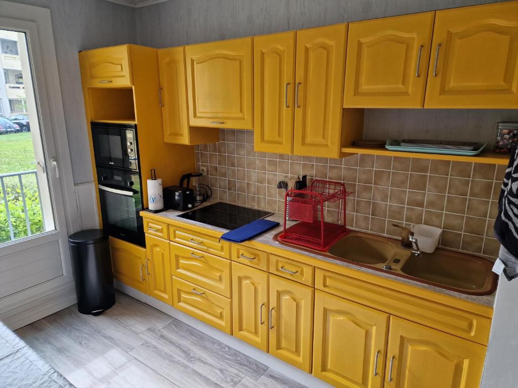uma cozinha com armários amarelos e um lavatório em Ian'Éliel Appart em Compiègne