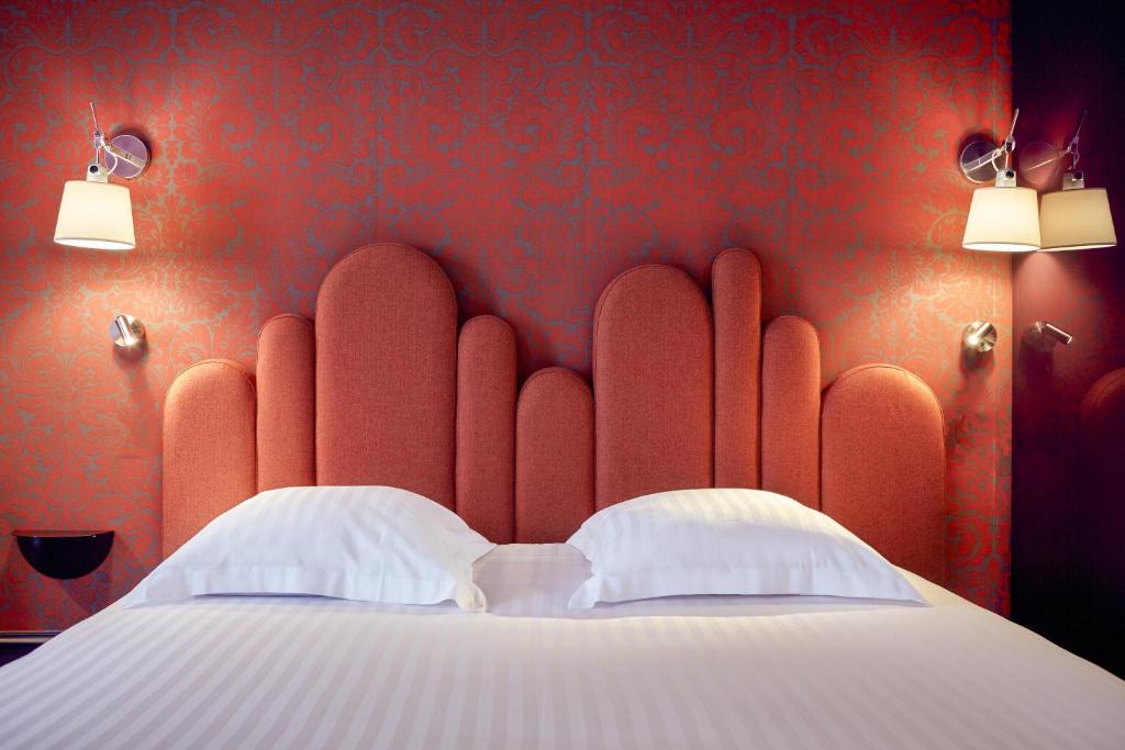 a red bedroom with a bed with two white pillows at Grand Hôtel du Midi Montpellier - Opéra Comédie in Montpellier