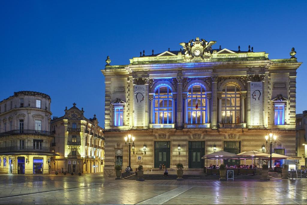 a large building with a clock on it at night at Grand Hôtel du Midi Montpellier - Opéra Comédie in Montpellier