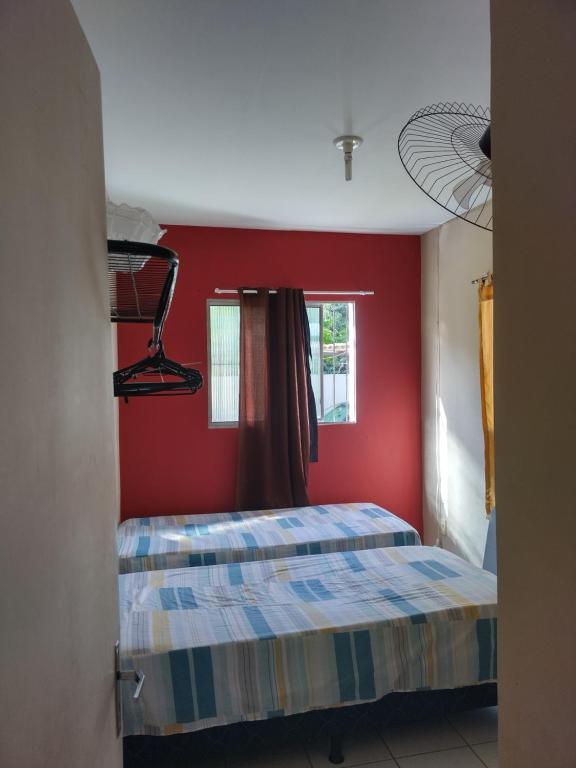 a bedroom with two beds and a red wall at Casa de praia para temporada in Paulista