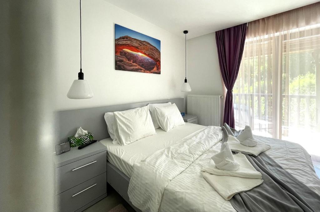 a bedroom with a white bed and a window at Mountain River Loft in Buşteni