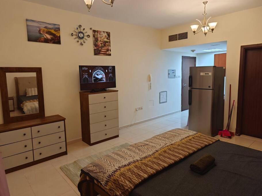 een slaapkamer met een bed, een koelkast en een dressoir bij Sea View Studio in Ajman 