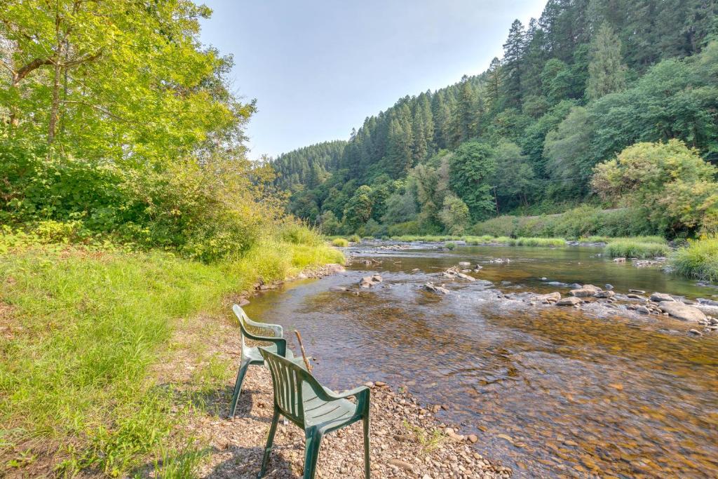 two chairs are sitting next to a river at Historic Mapleton Cottage with River Views and Hot Tub in Mapleton