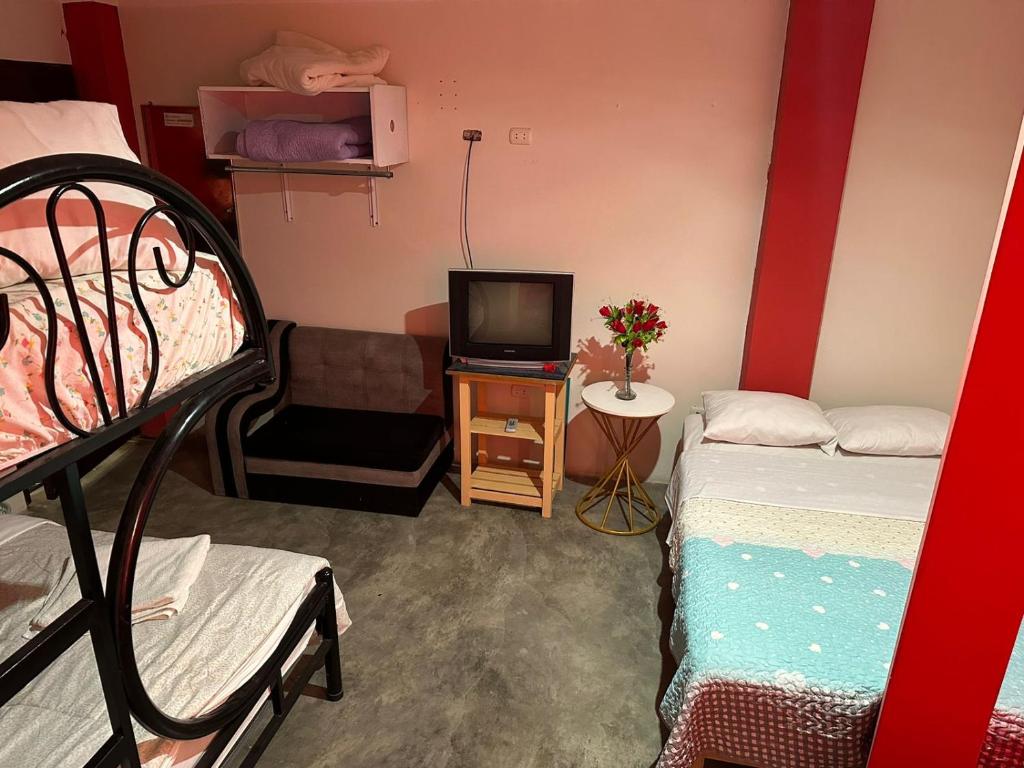 a small room with two beds and a tv at La Esquina de Doña Julia in Lima