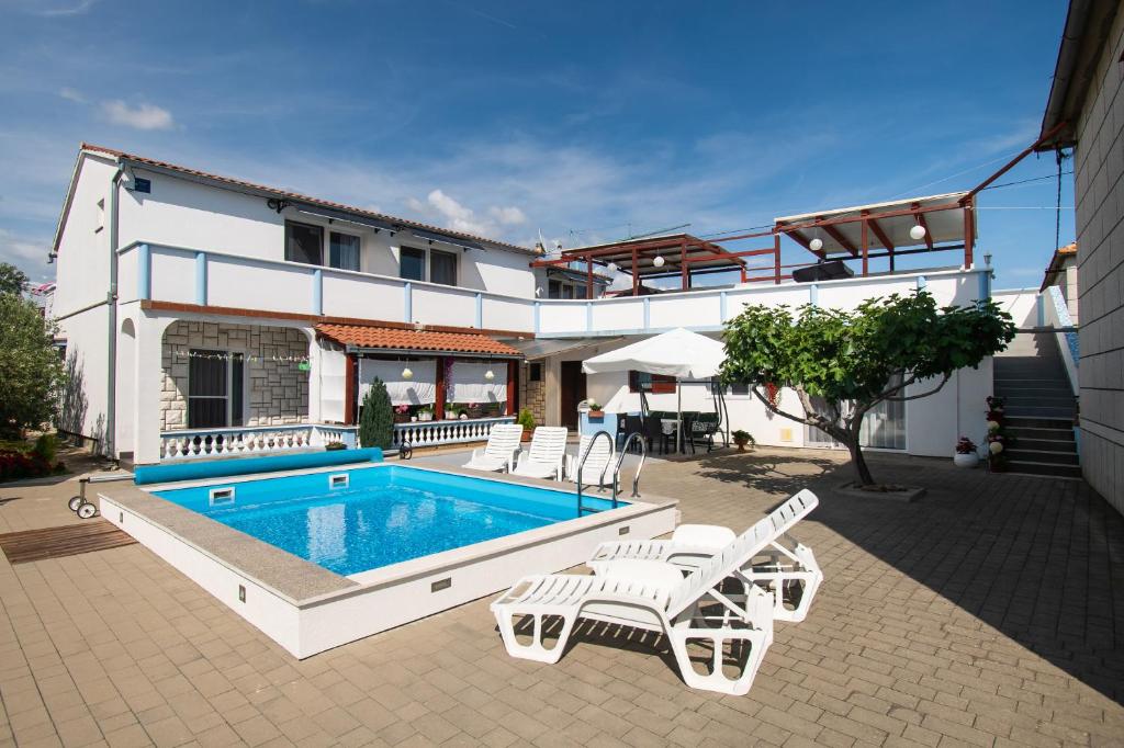 une maison avec une piscine, des chaises et une maison dans l'établissement Apartments Denis, à Tribunj