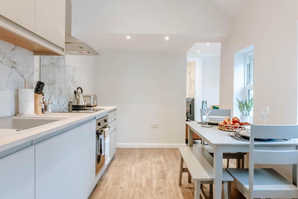 una cocina con armarios blancos y una mesa con frutas. en Mayfield Two - Central Harrogate Apartment en Harrogate