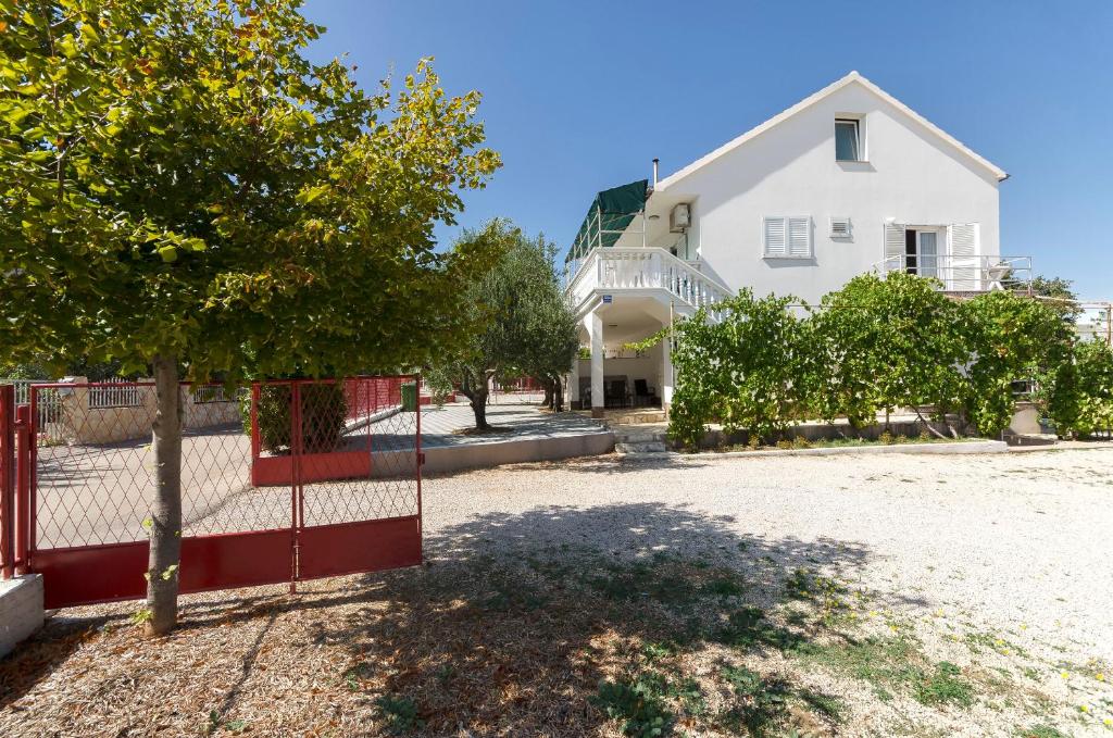 una casa blanca con una valla roja y árboles en Apartments Mirjana, en Vodice