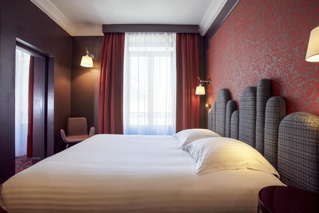 a bedroom with a large bed with red walls and a window at Grand Hôtel du Midi Montpellier - Opéra Comédie in Montpellier
