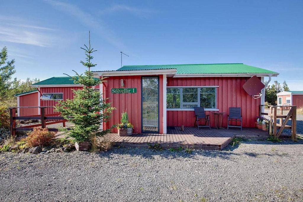 a red house with a porch and a deck at Sólvellir Holiday Home in Kjósahreppur