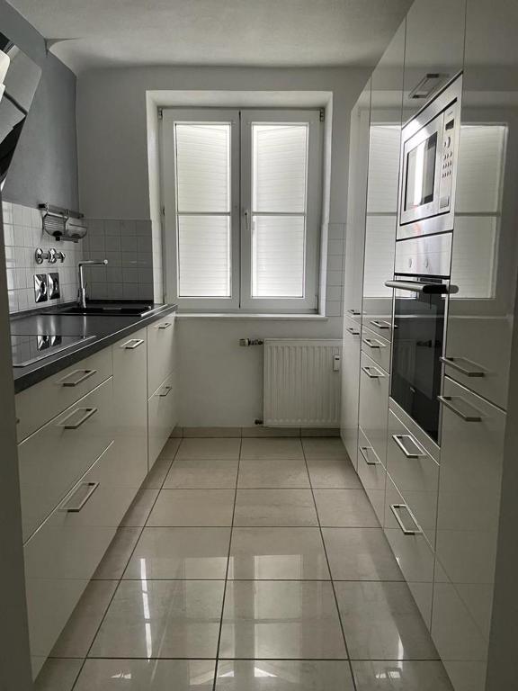 a kitchen with white cabinets and a large window at Apartment Lara in Friedrichshafen