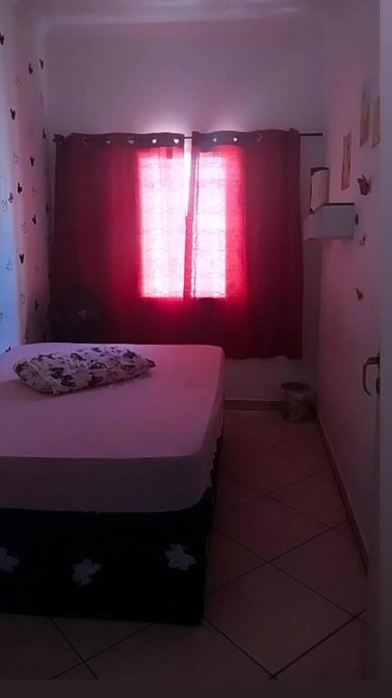 - une chambre avec un lit et une fenêtre rouge dans l'établissement Casa da Taty, à Tatuí