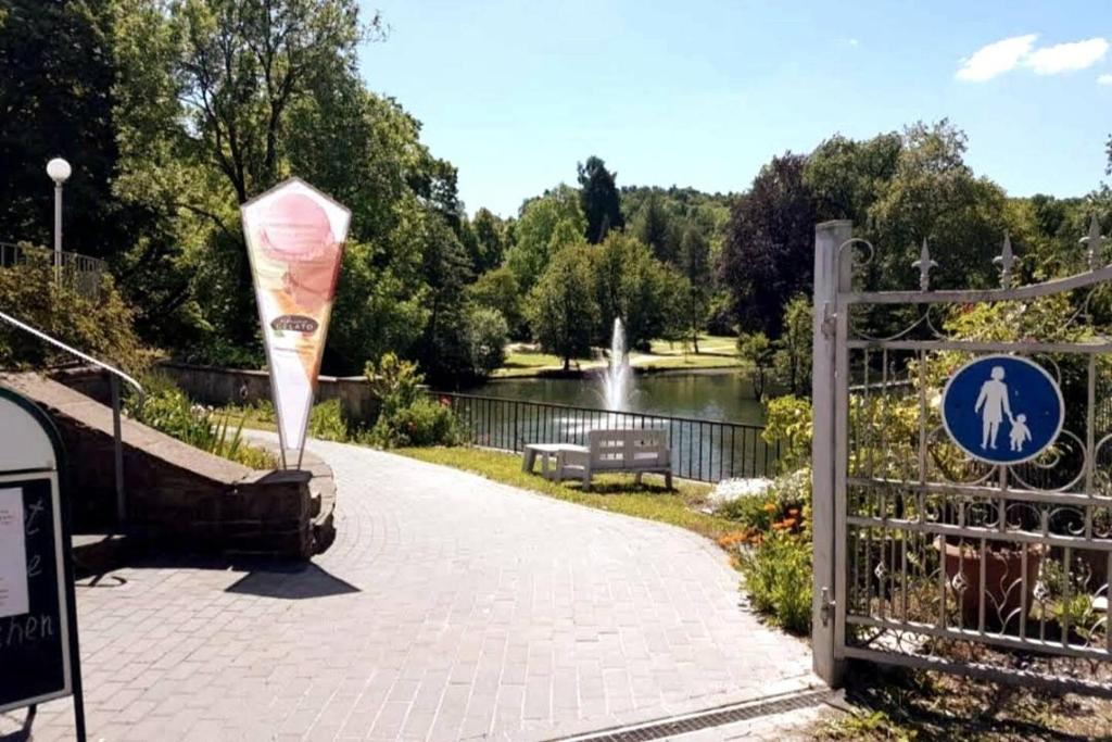 een park met een bankje en een hek met een bord bij Ferienwohnung 303 am Kasinopark in Georgsmarienhütte