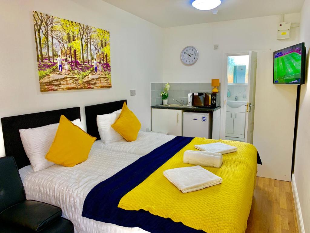 a bedroom with a large bed with yellow pillows at London Studio Apartments Close to Station NP2 in London