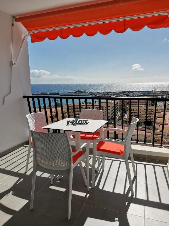 a table and chairs on a balcony with a view of the ocean at Appartement standing Vue panoramique OceanSight Beach 250m in Los Cristianos