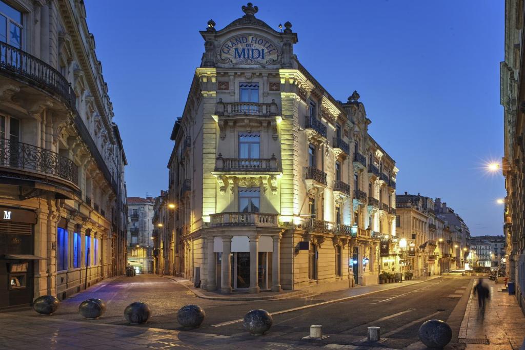 a tall building with a clock tower on a street at Grand Hôtel du Midi Montpellier - Opéra Comédie in Montpellier