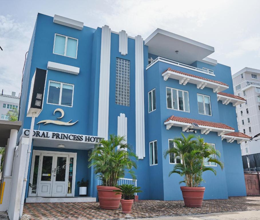 ein blaues Gebäude mit Palmen davor in der Unterkunft Coral Princess Hotel in San Juan