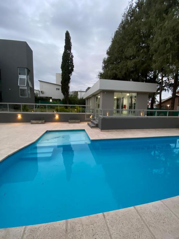 una gran piscina azul frente a una casa en Departamento nuevo con seguridad y pileta ,en villa allende a 15 del centro de Córdoba en Villa Allende