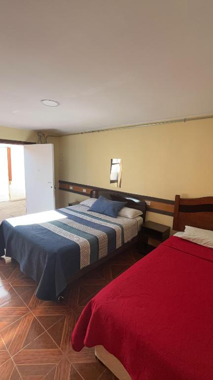 a bedroom with two beds and a red blanket at HOSTAL 469 in La Serena