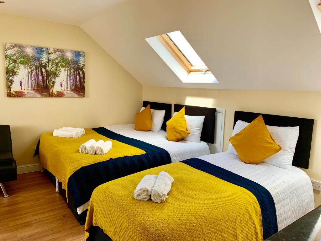 a bedroom with two beds with yellow and white sheets at London Studio Apartments, Private Bathroom, Kitchenette, Parking, NP7 in London