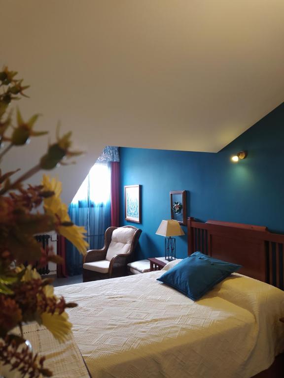 a bedroom with blue walls and a bed and a chair at HABITACIONES "el BOJ" in Colombres