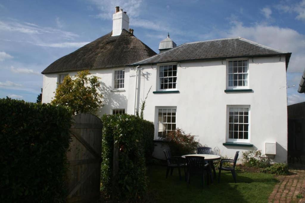 ein weißes Haus mit einem Tisch und Stühlen im Hof in der Unterkunft Travershes Holiday Cottage in Exmouth