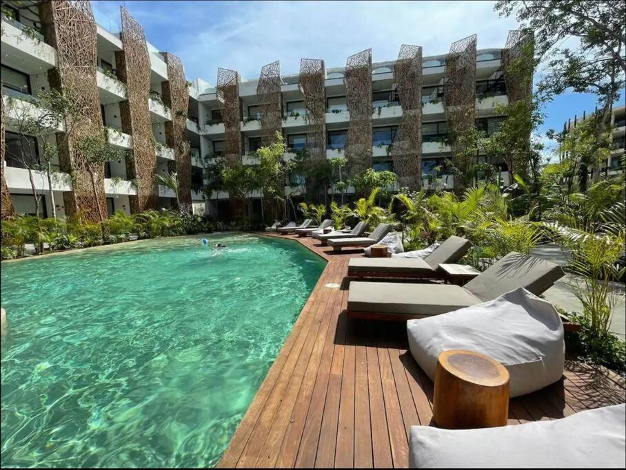 einen Pool mit Liegestühlen und einem Gebäude in der Unterkunft Jade Tulum Zen Residences - Premium XL Apartment in Tulum