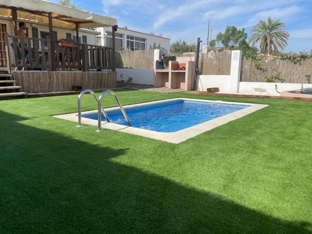 una piscina en un patio con césped verde en Chalet-home familiar "CAL ÍNDIA" "Pet friendly", en Sant Carles de la Ràpita