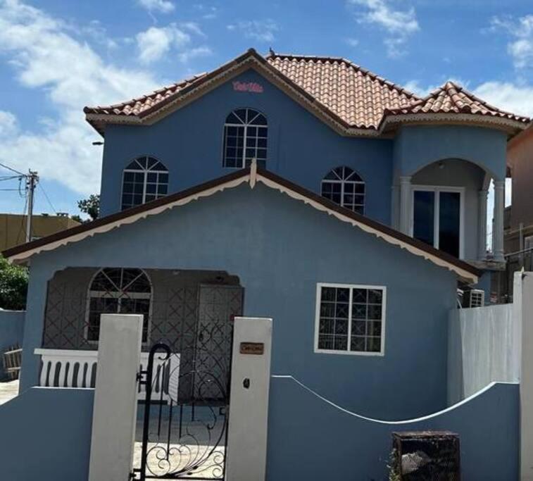 a blue house with a fence in front of it at Oak Villa Montego Bay2 King Room in Montego Bay